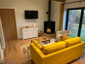 a yellow couch in a living room with a fireplace at Country Cottage with moat in Ingatestone