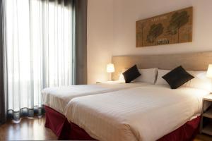 um quarto com uma grande cama branca e uma grande janela em MH Apartments Gracia em Barcelona