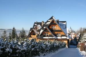 a large wooden house in the snow with snow at Holiday Home Krzysztoforow in Zakopane