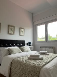 a white bedroom with two beds and two windows at Casa Xoubiña in Mos