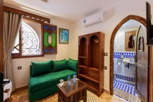 a living room with a green couch and a window at Riad Sultan Chefchaouen in Chefchaouen