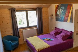 a bedroom with a bed and a blue chair at Aux Buis Gourmands in La Chapelle-en-Vercors