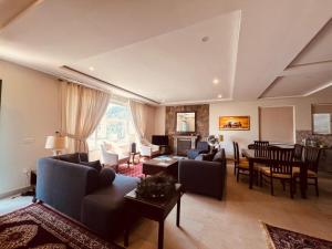 a living room with couches and a dining room at Haven Mushkpuri Terraces Khaira Gali - 3BR Home, Lawn, BBQ & Fireplace in Chhāngla Gali