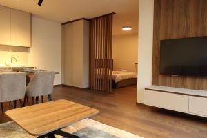 a living room with a television and a table with chairs at NUMA LIVING - Executive Suite in Kumanovo
