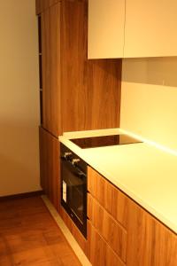 a kitchen with wooden cabinets and a stove top oven at NUMA LIVING - Executive Suite in Kumanovo