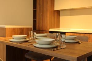 a wooden table with plates and bowls and glasses on it at NUMA LIVING - Executive Suite in Kumanovo +26 photos