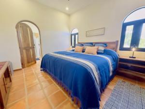 a bedroom with a bed with blue sheets and two windows at Near Beach Casita With Firepit in Los Barriles
