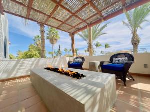 a living room with a fireplace on a patio with palm trees at Near Beach Casita With Firepit in Los Barriles