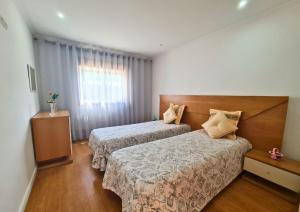 a hotel room with two beds and a window at Casa do Telhal in Vila Nova de Gaia