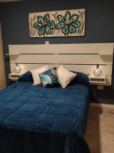 a bed with a blue comforter in a bedroom at El Refugio in La Falda +16 photos
