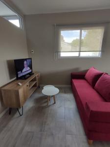 a living room with a red couch and a tv at El Refugio in La Falda