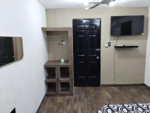 a room with a black door and a television at Casa Rota in Mérida