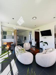 a living room with two white chairs and a tv at Mansión Altamirano - Hotel in Talavera