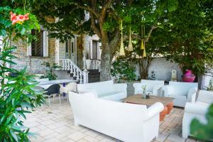 a patio with white chairs and tables and a tree at Maison de la Poupée in Afétai