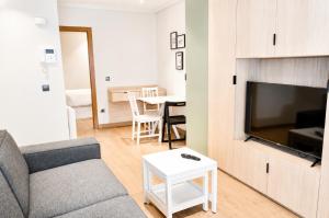a living room with a couch and a tv and a table at Apartamentos 19 Living in León