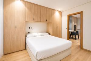 a bedroom with a white bed and wooden cabinets at Apartamentos 19 Living in León