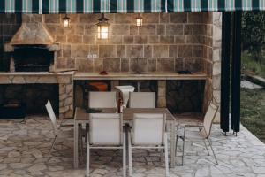 a patio with a table and chairs in front of a stone wall at Carob Breeze House in Krimovice