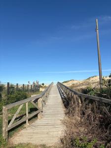 a wooden bridge leading to the beach at Costa Atlântico House in Garopaba