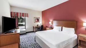 a hotel room with a bed and a flat screen tv at Aiken Midtown Hotel in Aiken