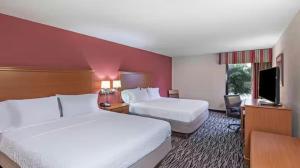 a hotel room with two beds and a flat screen tv at Aiken Midtown Hotel in Aiken