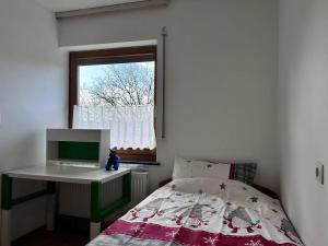 a bedroom with a bed and a desk and a window at Traumhaus in Küssaberg