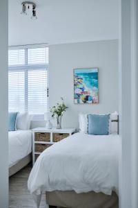 a white bedroom with a bed and a couch at 2 Bedroom Bloubergstrand Apartment with Ocean Views in Bloubergstrand