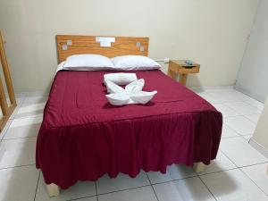 a bed with a red blanket and a white flower on it at HOTEL SANTA BARBARA PUERTO ilo in Ilo
