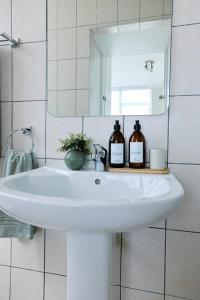 a bathroom sink with two bottles of wine on it at 2 Bedroom Bloubergstrand Apartment with Ocean Views in Bloubergstrand +25 photos