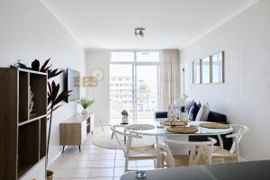 a white living room with a table and chairs at 2 Bedroom Bloubergstrand Apartment with Ocean Views in Bloubergstrand