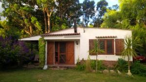 una pequeña casa blanca en medio de un patio en Las Palmeras, en Aguas Dulces