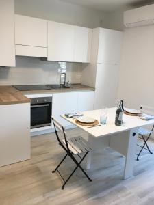 a kitchen with white cabinets and a white table and chairs at Studio Artemisia in Grado