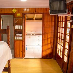 a room with a kitchen and a tv in a room at Pousada Halliny do Rosa in Praia do Rosa