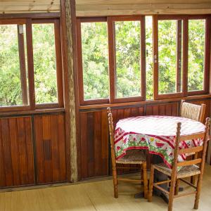 a table and chairs in a room with windows at Pousada Halliny do Rosa in Praia do Rosa