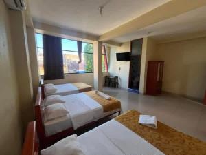a room with four beds and a flat screen tv at California Bambú in Iquitos