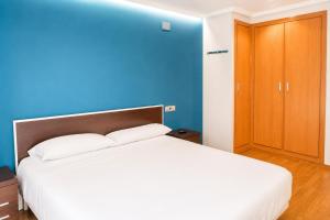 a bedroom with a white bed and a blue wall at Apartamentos 19 Living in León