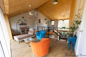 a living room with wooden ceilings and orange chairs at Aux Buis Gourmands in La Chapelle-en-Vercors