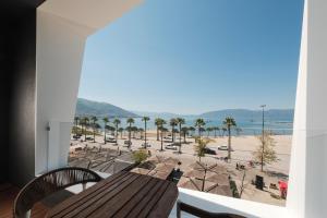 a balcony with a wooden table and chairs and a beach at Chic Boutique Hotel Vlore in Vlorë