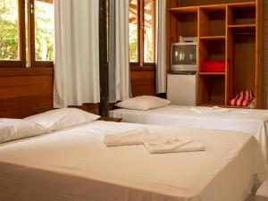 two white beds in a room with a tv at Pousada Halliny do Rosa in Praia do Rosa +84 photos