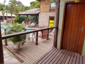 a porch with a wooden door and a swimming pool at Pousada Halliny do Rosa in Praia do Rosa