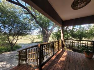 a porch with a wooden fence and a tree at Rustic Gate Lodge and Campsite in Maun