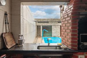 a kitchen with a sink and a brick wall at House with Pool in BH for Groups and Families in Belo Horizonte