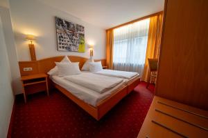 a bedroom with a bed with white sheets and a window at Hotel Mondial Munich in Munich