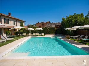 ein Swimmingpool im Garten mit Sonnenschirmen in der Unterkunft Le Volpaie in San Gimignano