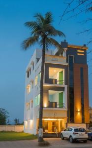 a car parked in front of a building with a palm tree at De Majestic SSK Paradise Beach Villa in Pondicherry