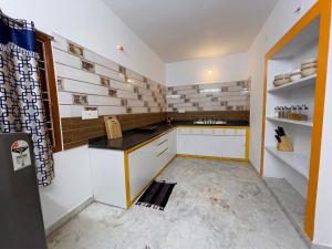a kitchen with white cabinets and a black counter top at De Majestic SSK Paradise Beach Villa in Pondicherry