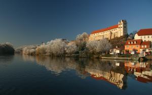 a castle on a hill next to a body of water at Ferienwohnung Petersbrunnen in Zaschwitz