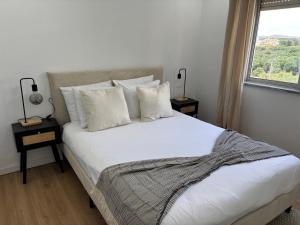 a bedroom with a white bed with pillows and a window at Casa Borges in Quelfes