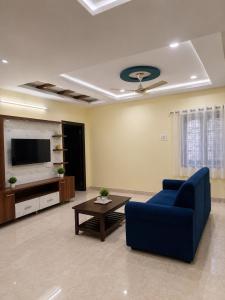 a living room with a blue couch and a tv at Gachi Ghar Gachibowli 2 BHK in Hyderabad