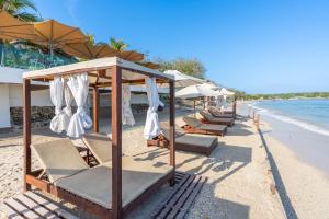 a row of lounge chairs and umbrellas on a beach at Hotel Tropical Inn in Tierra Bomba