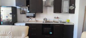 a kitchen with black cabinets and a sink and a refrigerator at Essa apartament in Brzeg